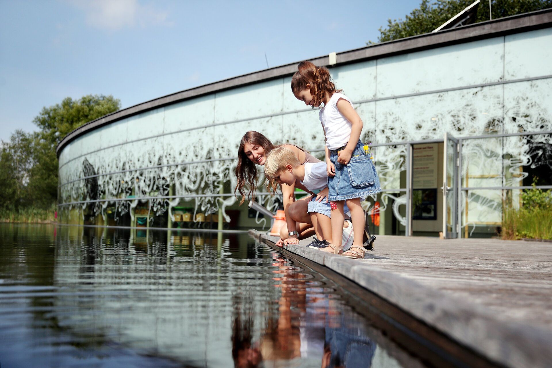 Eine fröhliche Familie genießt einen sonnigen Tag am Wasser, während die Kinder neugierig die glitzernden Wellen beobachten. Die harmonische Verbindung von Natur und Spiel lädt dazu ein, die Schönheit der Umgebung zu erkunden und unvergessliche Momente zu erleben.