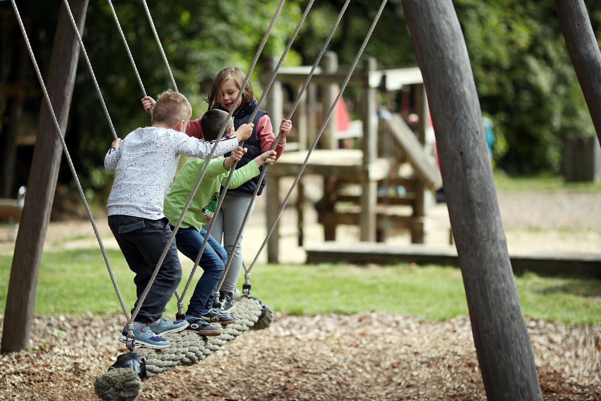 Drei Jungen stehen auf einem Spielgerät und schaukeln gemeinsam im Naturpark Sparbach. 