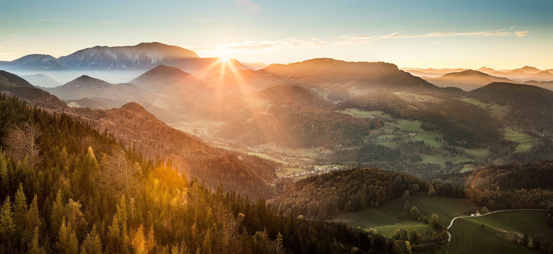 Die sanften Hügel und majestätischen Berge der Hohen Wand erstrahlen im warmen Licht der Morgensonne. Ein atemberaubender Blick über die weite Landschaft lädt dazu ein, die frische Bergluft zu genießen und die Ruhe der Natur zu erleben.