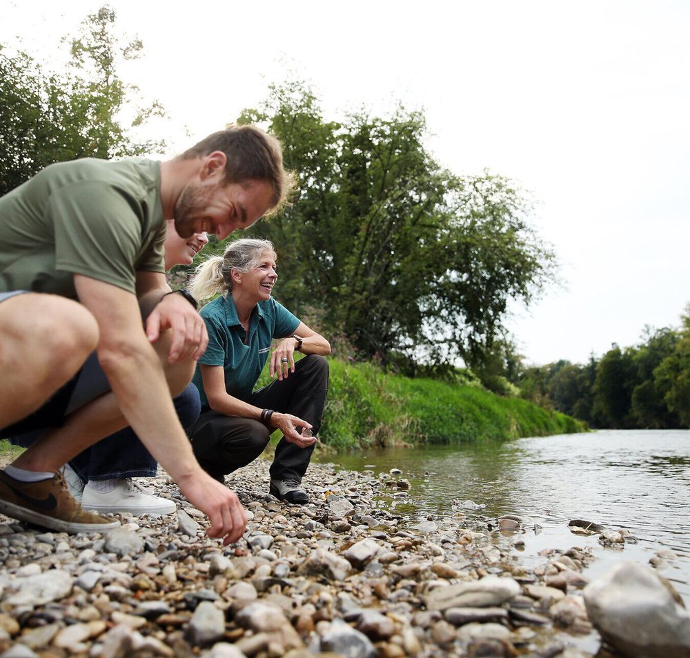 Mehrere Person hocken direkt an einem Fluss im Naturpark Ybbstal im Mostviertel.