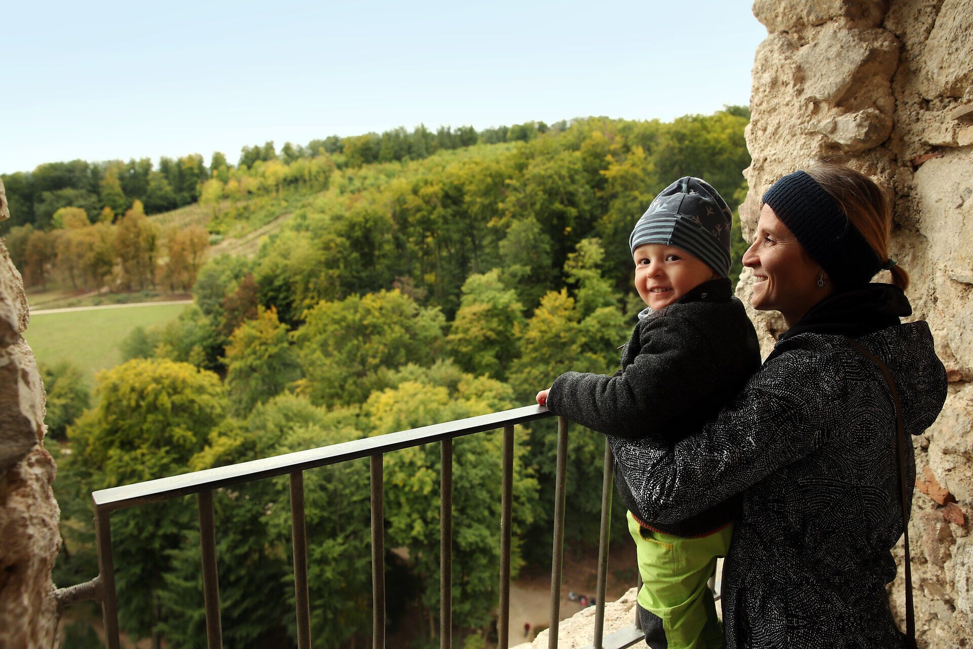 Ein Mutter hält ihr Kind fest, gemeinsam Blicken sie von der Ruine Johannstein Richtung Schaugehege im Naturpark Sparbach. 