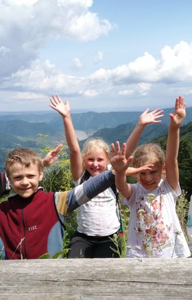 Mehrere Kinder winken glücklich in die Kamera, im Hintergrund sind die schönen Hügeln des Naturparks zu sehen.