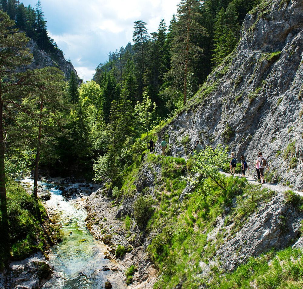 Die sanften Hügel und majestätischen Felsen umarmen den klaren Fluss, der durch die grüne Landschaft fließt. Wanderer genießen die frische Bergluft und die atemberaubenden Ausblicke, während sie auf schmalen Pfaden die Schönheit der Natur erkunden.