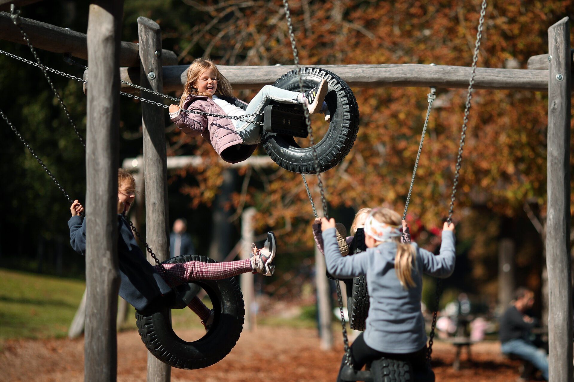 Mehrere Mädchen sitzen auf verschiedenen Schaukeln auf einem Abenteuerspielplatz im Naturpark Sparbach. 