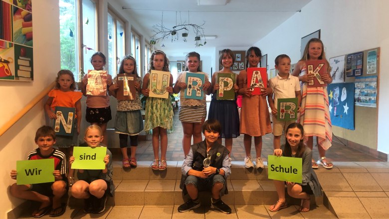 Volksschul-Kinder mit Naturpark Schildern auf der Schul-Stiege