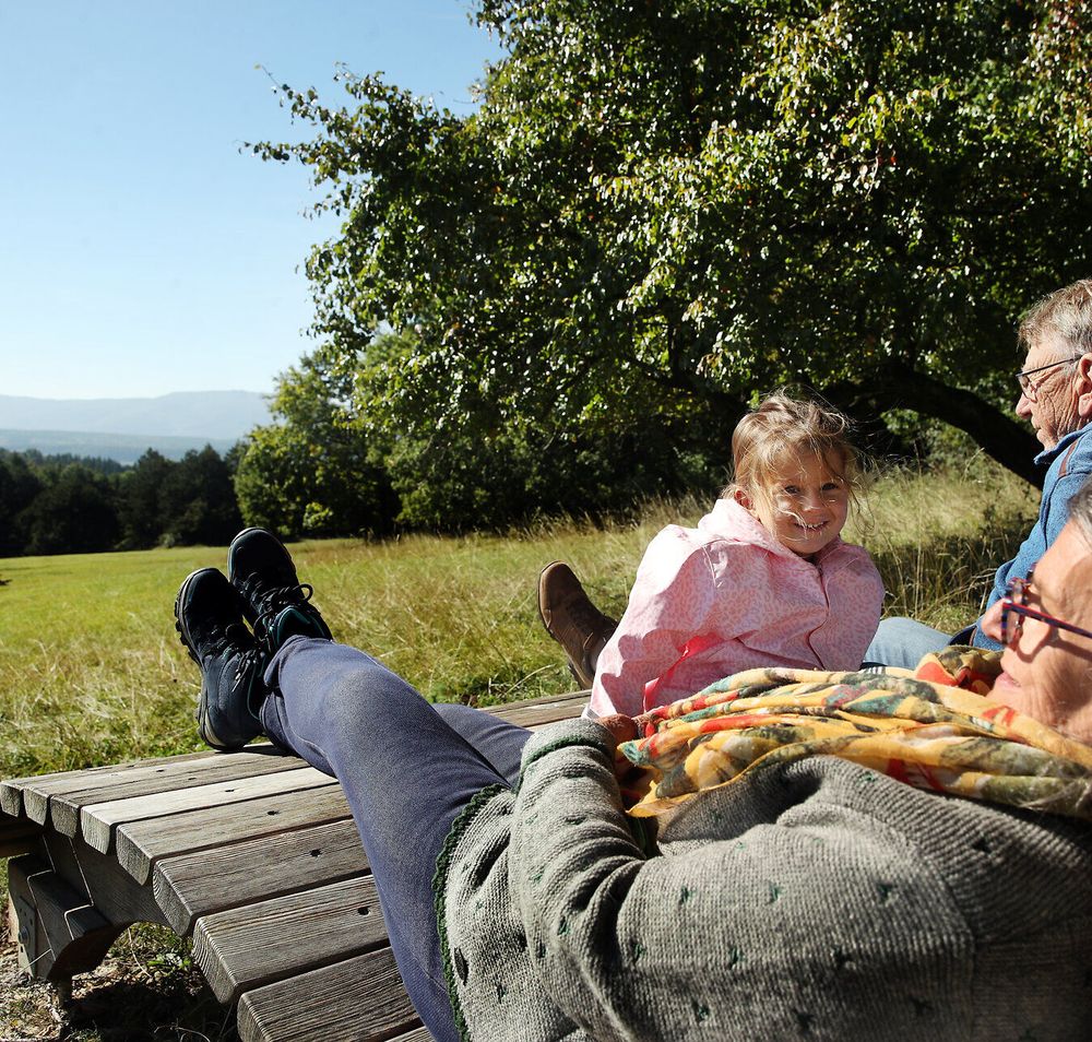 Großeltern machen gemeinsam mit ihrem Enkelkind eine Pause auf den Liegen der Dianawiese im Naturpark Sparbach. 